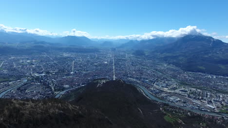 Volando-Sobre-La-Ladera-De-Una-Montaña-Con-Vistas-A-La-Ciudad-De-Grenoble